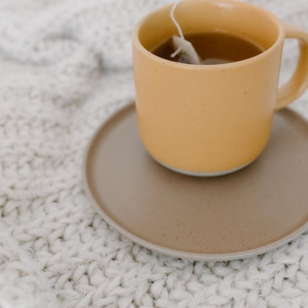 Cup of herbal tea next to a soft blanket.